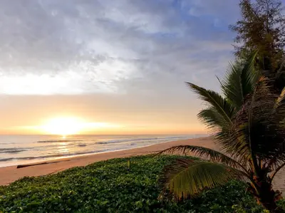 a sunset on a beach with a palm tree at Infinity Blue Phuket by Elite Havens in Natai Beach