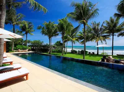 a swimming pool with palm trees and the ocean at Villa Nandana by Elite Havens in Natai Beach