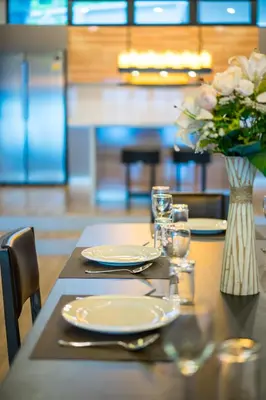 a table with plates and a vase of flowers on it at Nakara Hill Phuket in Chalong