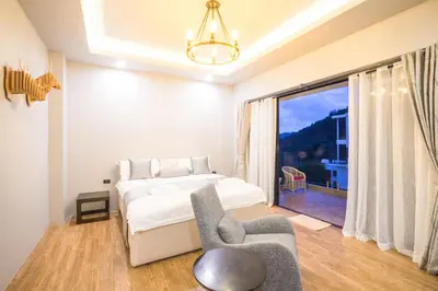 a bedroom with a bed and a chair and a window at Nakara Hill Phuket in Chalong