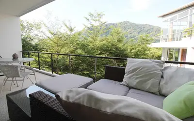 a couch sitting on a balcony with a view at Zen Hillside Self Service Apartment in Kamala Beach