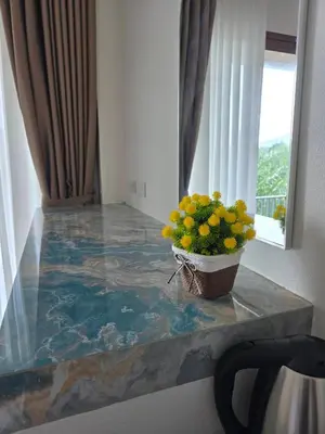 a vase of yellow flowers on a counter next to a window at Baannai Lake View Resort in Ao Nang Beach