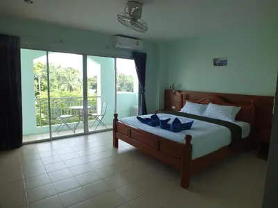 a bedroom with a bed and a view of a balcony at saithong guesthouse in Rawai Beach