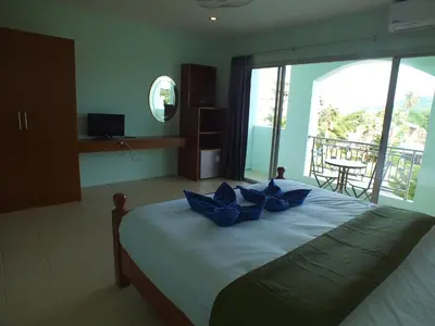 a bedroom with a bed with blue pillows on it at saithong guesthouse in Rawai Beach