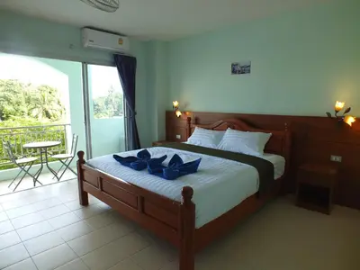 a bedroom with a bed with blue pillows on it at saithong guesthouse in Rawai Beach