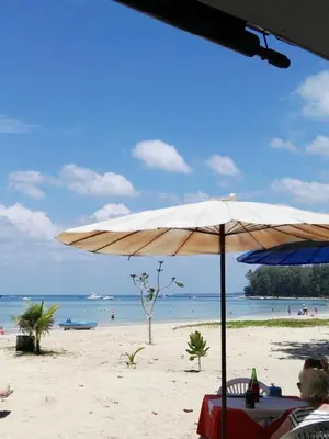 a beach with an umbrella and people on the beach at The Title Residencies Naiyang Pool View in Nai Yang Beach