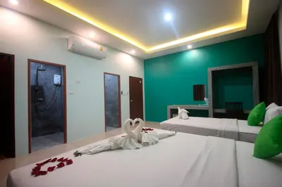 a bedroom with two beds with white sheets and a green wall at The Aireen Hotel in Ao Nang Beach