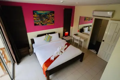 a bedroom with a white bed with a pink wall at OK Phuket in Kata Beach