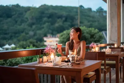 a woman sitting at a table in a restaurant at Mandarava Resort and Spa, Karon Beach in Karon Beach