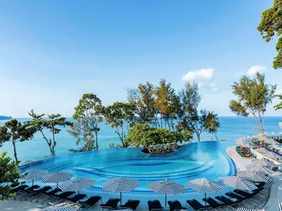 a swimming pool with umbrellas and the ocean at Pullman Phuket Arcadia Naithon Beach in Nai Thon Beach