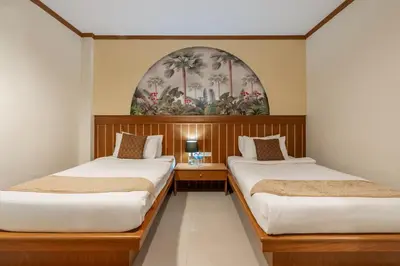 two beds in a room with a painting on the wall at The Eden Park in Patong Beach