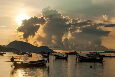 a group of boats sitting in the water at sunset at Ya Nui Resort - SHA EXTRA Plus in Rawai Beach