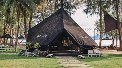 a black tent with chairs in the grass at The Mangrove Phuket by Blu Monkey in Panwa Beach