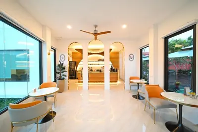 a hotel lobby with tables and chairs and a bed at The Kiri Villas Resort in Thalang