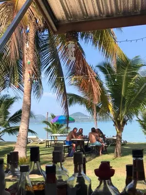 a group of people sitting at a table under palm trees at Koh Yao Candy House in Ko Yao Yai