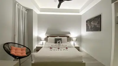 a bedroom with a white bed and a chair at Twin Villas Seaview Kata in Kata Beach