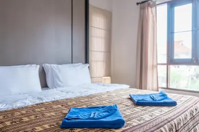 a bed with two blue towels on it with a window at Sea eagle pool villa in Ao Nang Beach
