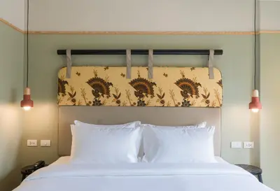 a bed with two white pillows and a headboard at The Blanket Hotel Phuket Old Town in Phuket Town