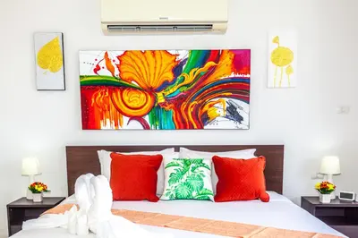 a bedroom with a bed with red pillows and a painting at Wazza's Patong Apartment, Smart TV and Fast Wi-Fi in Patong Beach