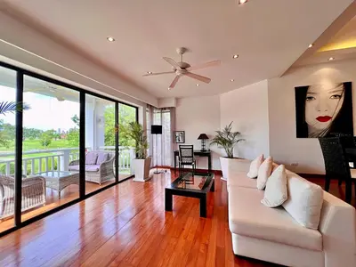 a living room with a white couch and a ceiling fan at Allamanda Laguna Phuket by RESAVA in Bang Tao Beach