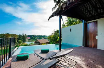 a deck with chairs next to a swimming pool at SUNSURI PHUKET, Nai Harn Beach in Nai Harn Beach