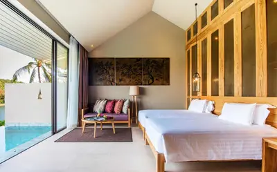 a bedroom with a bed and a couch and a window at SUNSURI PHUKET, Nai Harn Beach in Nai Harn Beach