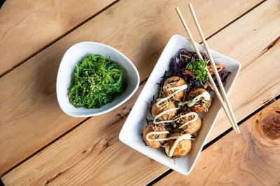 a table with two plates of food and a bowl of greens at The Z Nite Hostel in Phuket Town