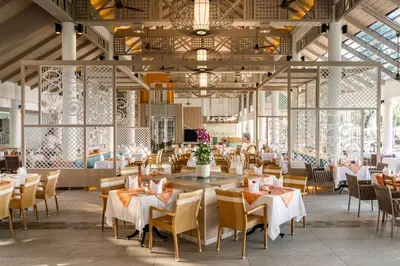 a restaurant with white tables and chairs and a large ceiling at Katathani Phuket Beach Resort - SHA Extra Plus in Kata Beach