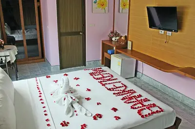 a cake with red roses on top of a bed at Baan Ketkeaw Guest House 2 in Patong Beach