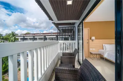 a balcony with chairs and a bed and a bedroom at Aonang Buri Resort in Ao Nang Beach