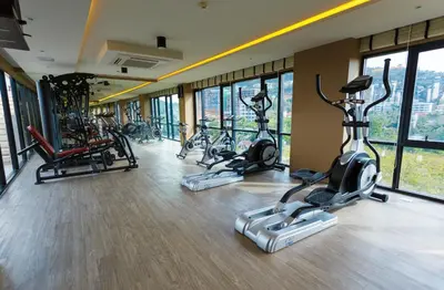 a gym with several exercise bikes in a room with windows at The Aristo by Holy Cow, 2-BR, 60 m2, pool view in Surin Beach