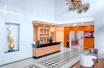 a lobby with a counter with a checkered floor at Phoenix Hotel Karon Beach in Karon Beach