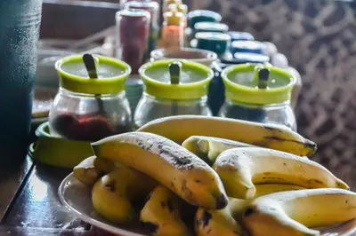 a plate of bananas sitting on a table with jars at Baan Tubkaek Hotel in Tab Kaek Beach