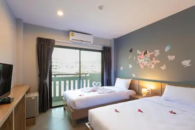 a bedroom with two beds and a window with butterflies on the wall at iNest Poshtel in Kata Beach