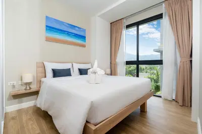 a bedroom with a large white bed and a large window at Diamond Condominium Bangtao Beach in Bang Tao Beach