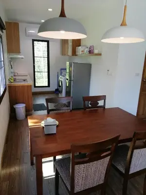 a kitchen and dining room with a wooden table and chairs at Twin Villa in Ban Muang Mai