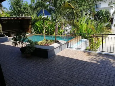 a swimming pool with plants and a fence at Twin Villa in Ban Muang Mai