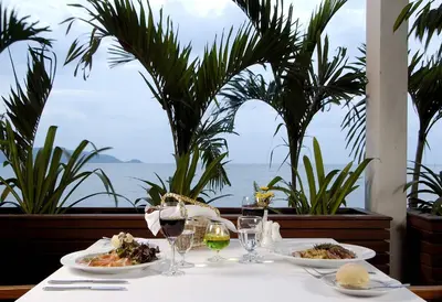 a table with plates of food and wine glasses on it at Sunset Beach Resort in Patong Beach
