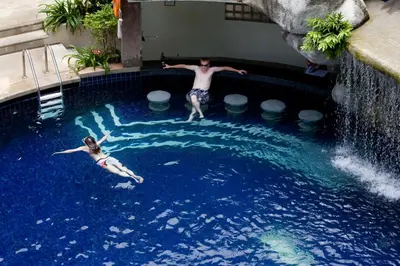 a man and a woman swimming in a swimming pool at Sunset Beach Resort in Patong Beach