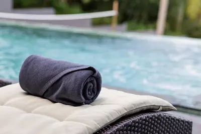 a towel sitting on a wicker chair next to a swimming pool at Braya Villa in Ko Yao Yai