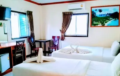 a hotel room with two beds and a table and chairs at Golden Bee PhiPhi in Phi Phi Don