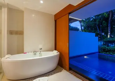 a bath tub in a bathroom with a large window at La Flora Resort Patong in Patong Beach