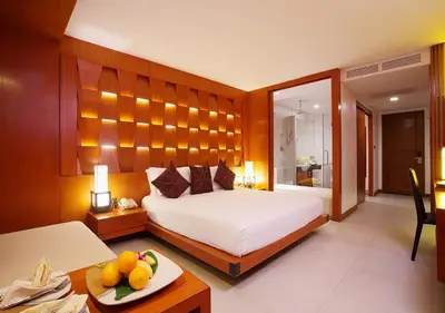 a bedroom with a bed and a table with a plate of fruit at La Flora Resort Patong in Patong Beach