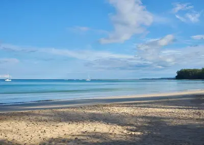 a beach with two boats in the water at Nai Yang Beach Resort and Spa in Nai Yang Beach