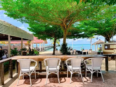 a bar with chairs and the ocean in the background at Baan Taranya Koh Yao Yai Resort in Ko Yao Yai