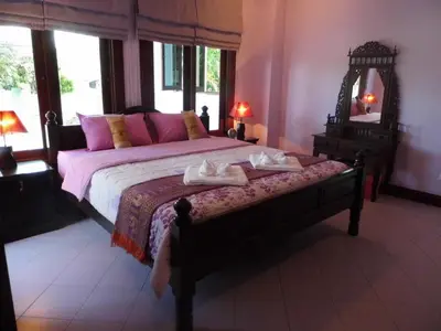 a bedroom with a bed with pink pillows and a mirror at Majestic Villas Guesthouse Phuket. in Rawai Beach