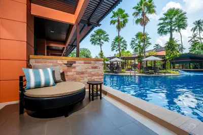 a resort swimming pool with a chair next to a table at Courtyard by Marriott Phuket, Patong Beach Resort in Patong Beach