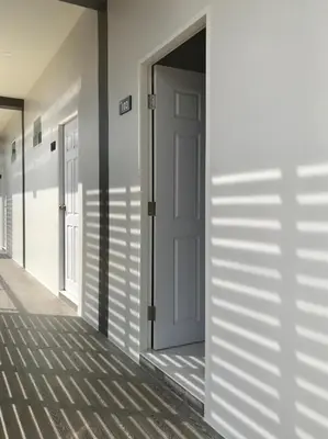 a hallway with doors and shadows on the wall at Airport Pearl Residence in Nai Yang Beach