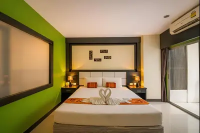 a bedroom with a large bed with green walls at EX-IT Inn in Patong Beach