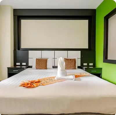 a bedroom with a large white bed with green walls at EX-IT Inn in Patong Beach
